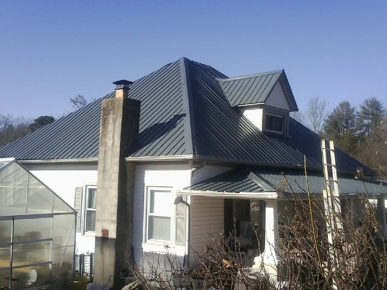 Dark blue standing seam metal roof on a white farmhouse with dormer — Slate & Tile Roof Repair by Roofing Brothers in Weyers Cave