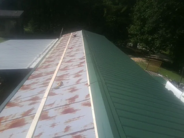 Old rusted panels beside newly installed green metal roofing — Wind Damage Roof Repair by Roofing Brothers in Weyers Cave