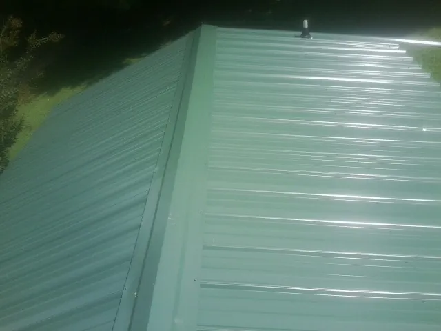 New green metal panels meeting at the ridge of a roof — Flat Roof Repair work by our crew in Weyers Cave