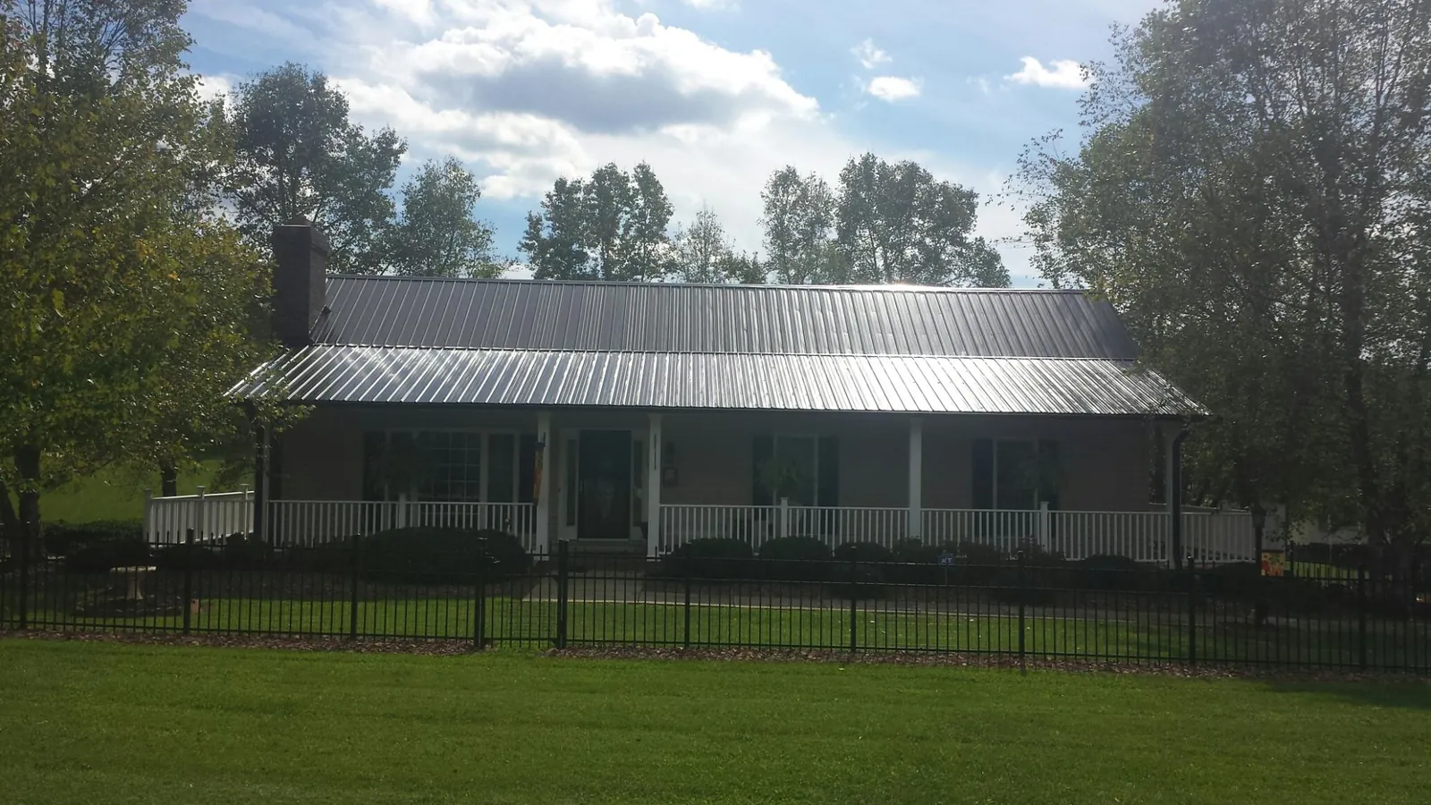 Gray metal roof on a brick ranch with a full width front porch — Gutter Guard Installation work by our crew in Weyers Cave