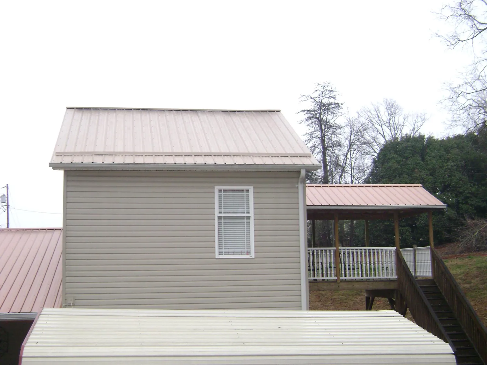 Tan metal roofs on a two story addition and attached porch, from a Roof Replacement job in Weyers Cave