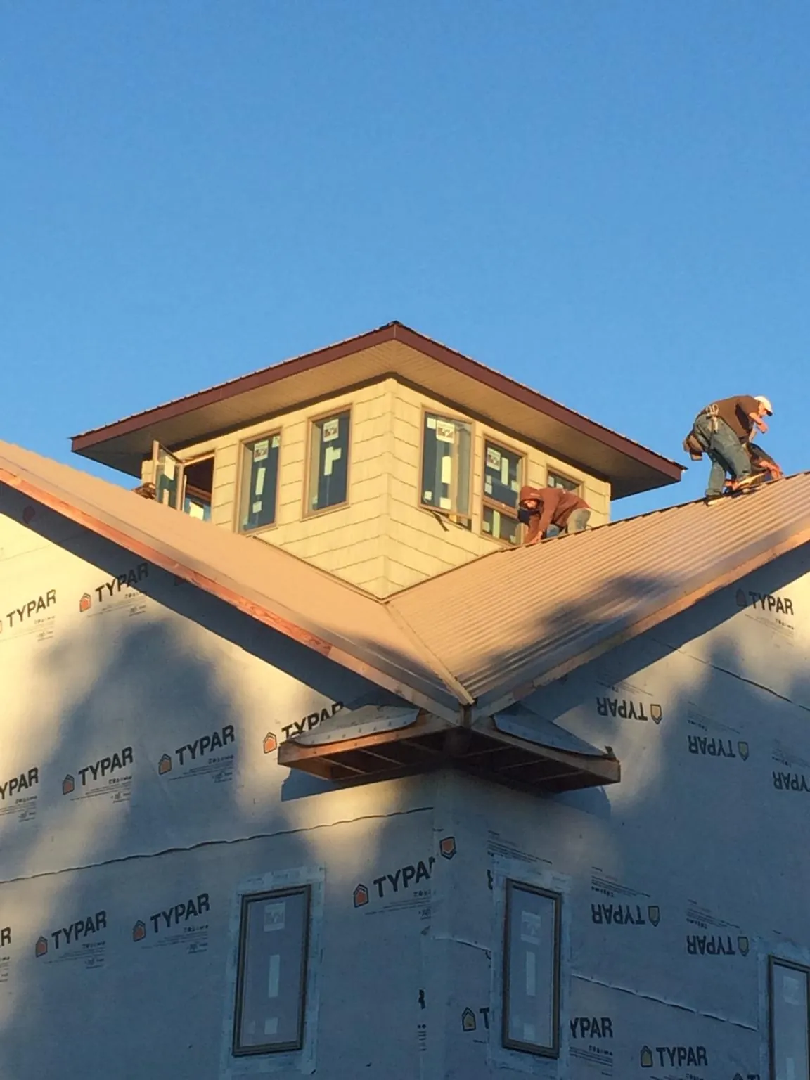 Roofers working around a rooftop cupola on a new metal roof at sunset — Roof Waterproofing in Weyers Cave by Roofing Brothers